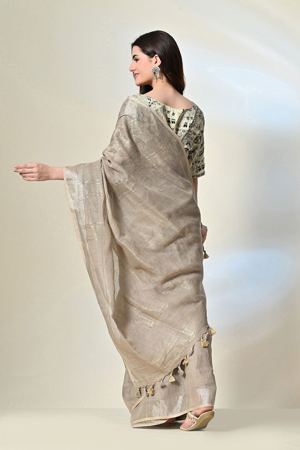 Elegant grey linen saree with tassels, dyed organically with pomegranate, enhanced by gold accents and handwoven details; suitable for dry cleaning.