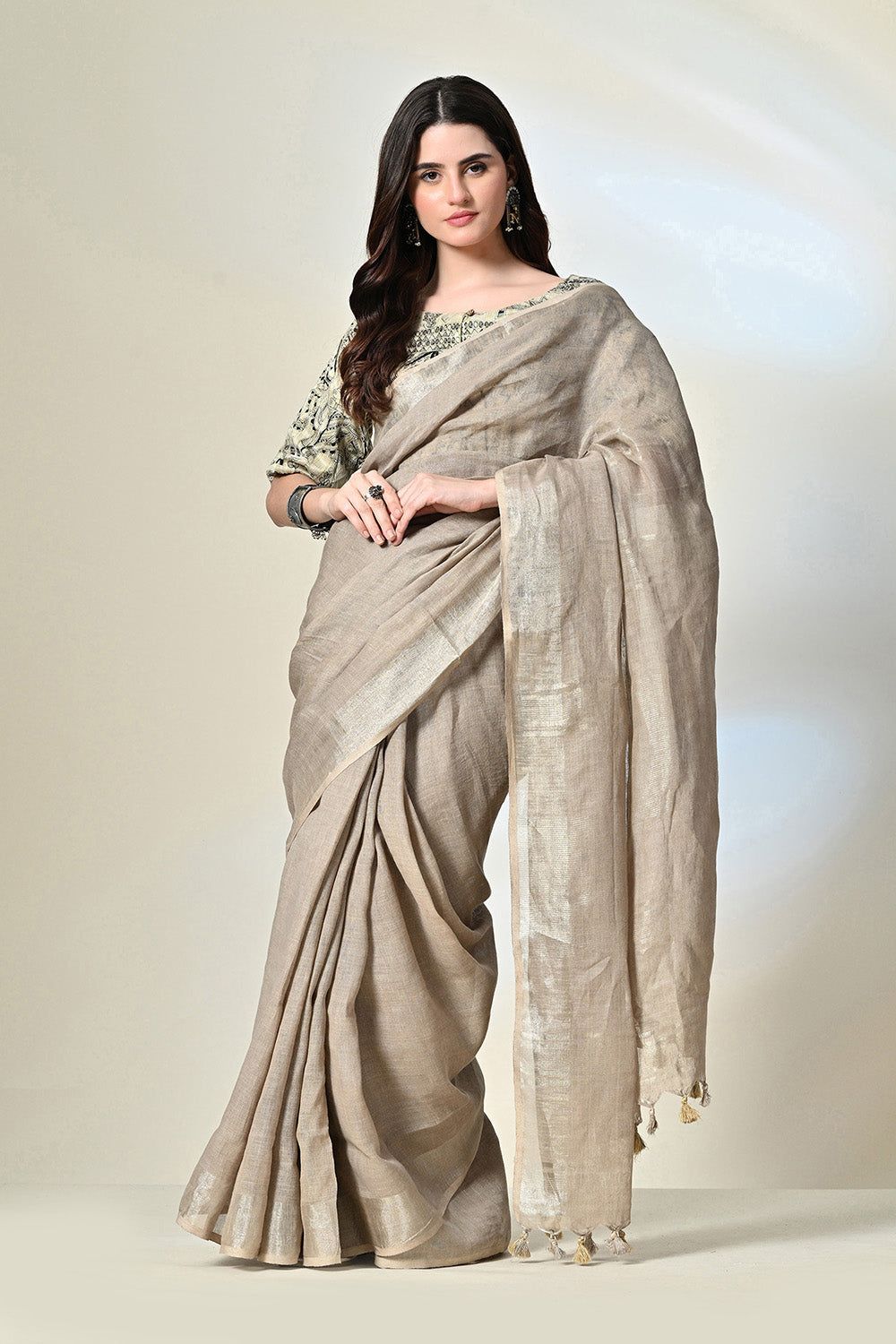Elegant grey linen saree with tassels, dyed organically with pomegranate, enhanced by gold accents and handwoven details; suitable for dry cleaning.