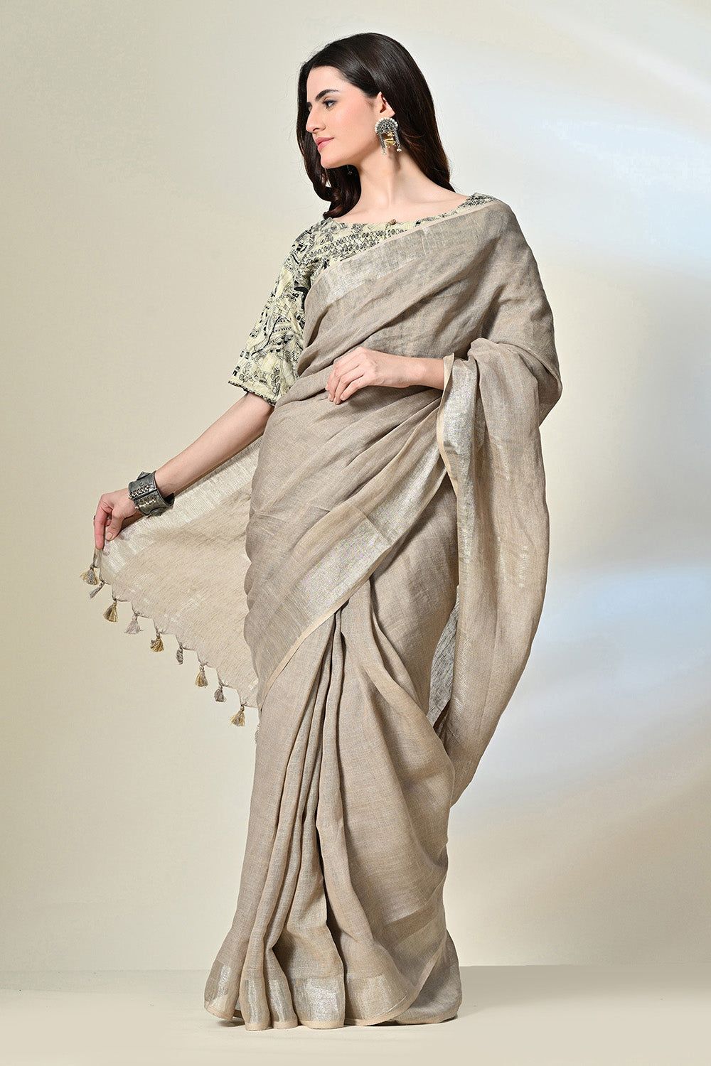 Elegant grey linen saree with tassels, dyed organically with pomegranate, enhanced by gold accents and handwoven details; suitable for dry cleaning.