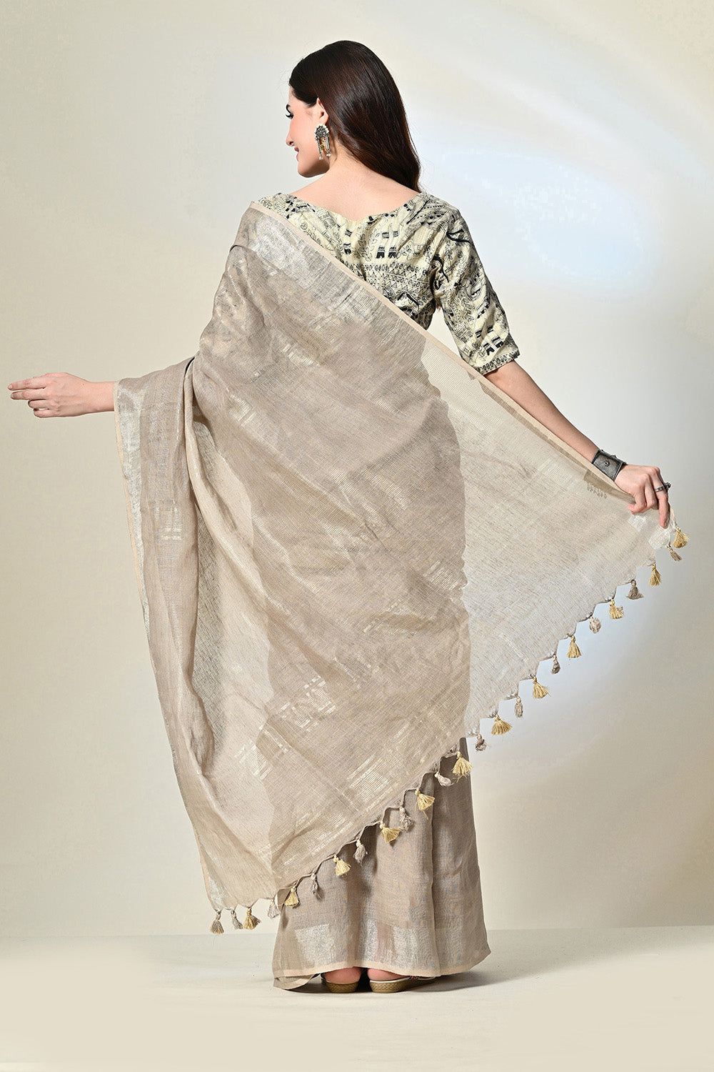 Elegant grey linen saree with tassels, dyed organically with pomegranate, enhanced by gold accents and handwoven details; suitable for dry cleaning.