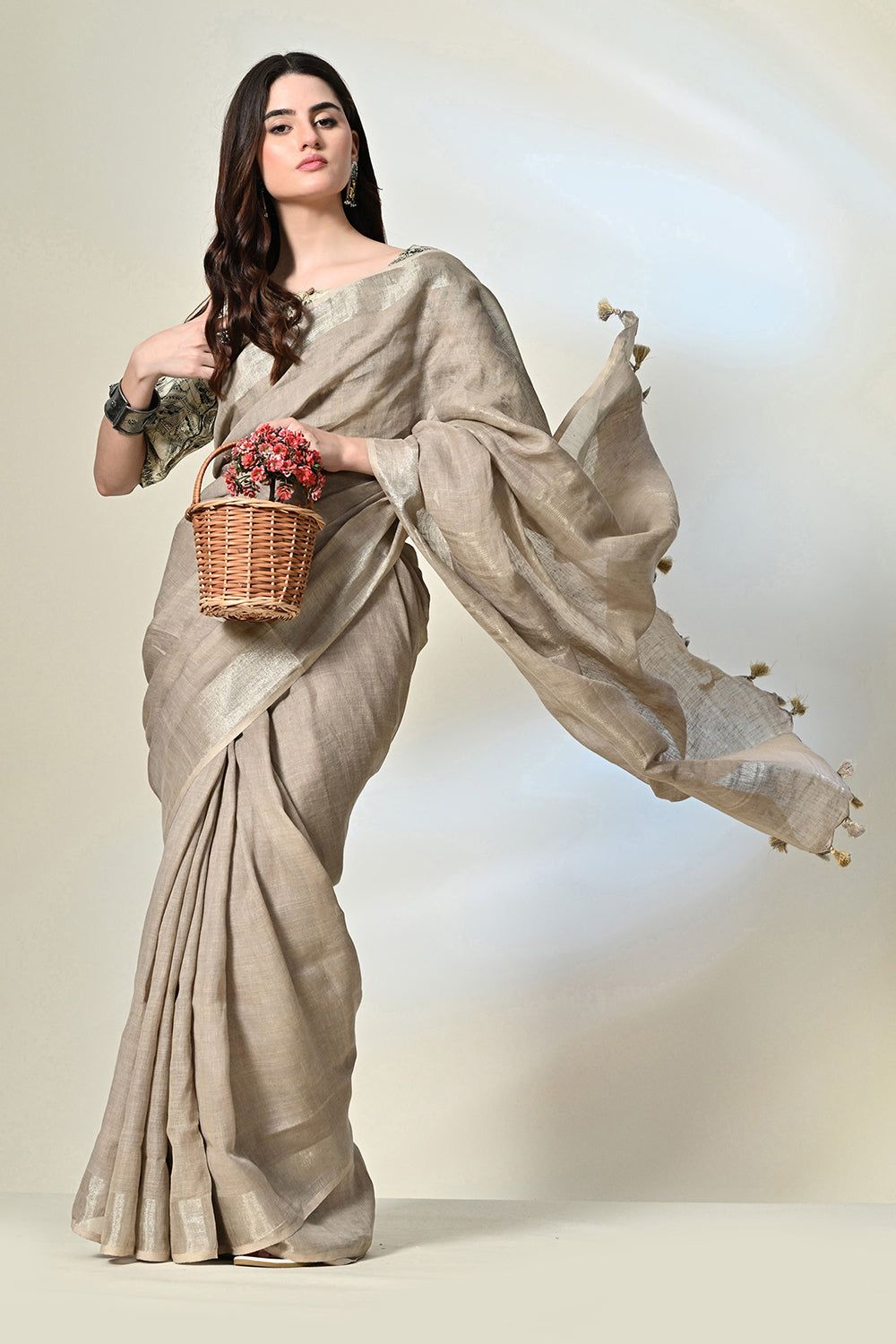 Elegant grey linen saree with tassels, dyed organically with pomegranate, enhanced by gold accents and handwoven details; suitable for dry cleaning.